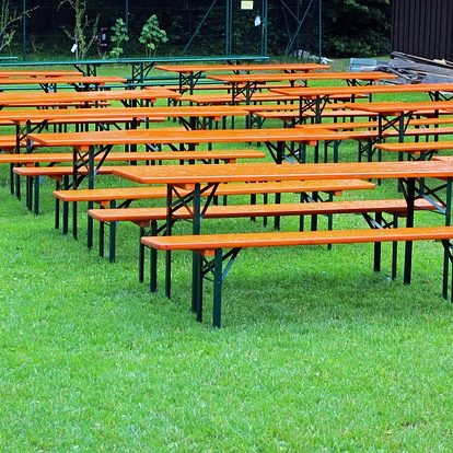 Bänke mit orangefarbenen Tischplatten auf grünem Rasen angeordnet.