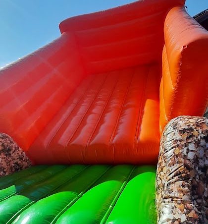 Bunte Hüpfburg in Form eines Schiffs mit Rutschen und Spielbereichen.