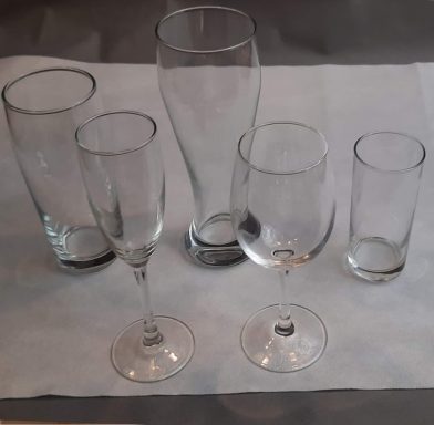 Verschiedene Gläser in unterschiedlichen Größen auf einem weißen Tisch.