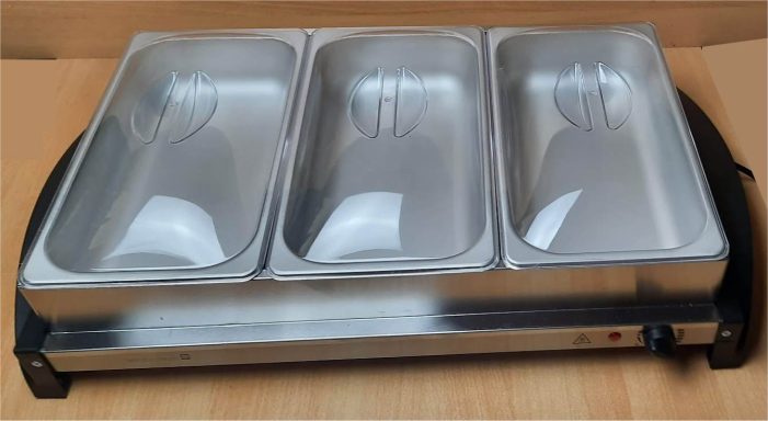 Drei rechteckige Edelstahltiegel auf einem beheizten Buffetständer.